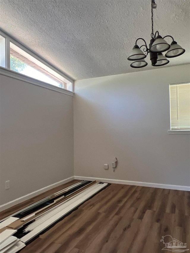 unfurnished room featuring a textured ceiling, lofted ceiling, a chandelier, and hardwood / wood-style flooring