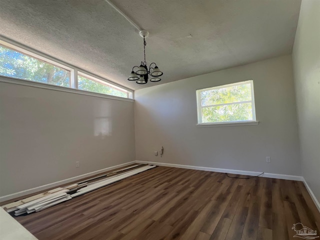 unfurnished room featuring lofted ceiling, a notable chandelier, a textured ceiling, and wood finished floors