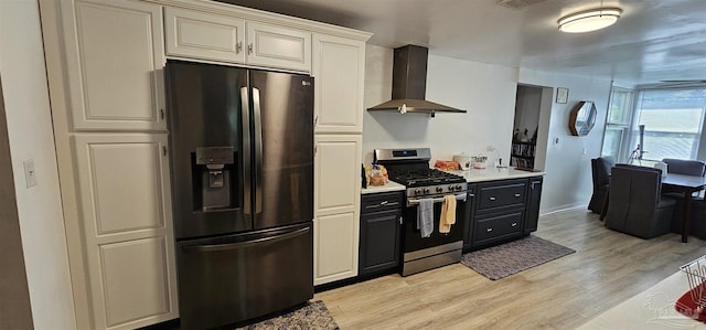 kitchen with stainless steel appliances, light hardwood / wood-style floors, and wall chimney exhaust hood