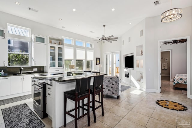 kitchen featuring white cabinetry, a center island, stainless steel range oven, pendant lighting, and a breakfast bar area