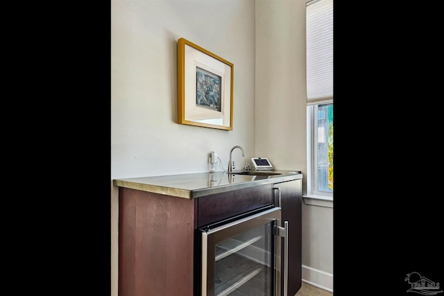 bar featuring wine cooler, dark brown cabinetry, and sink