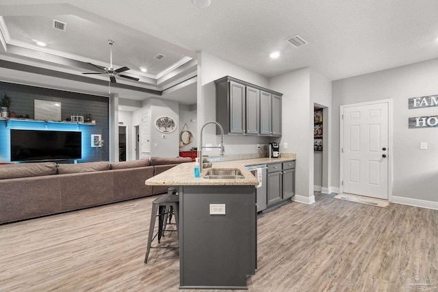 kitchen with sink, a breakfast bar, dishwasher, gray cabinets, and light wood-type flooring