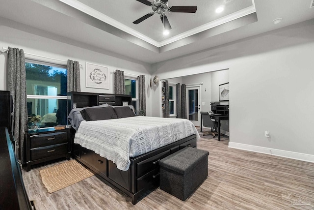 bedroom featuring hardwood / wood-style floors, ceiling fan, a raised ceiling, and crown molding