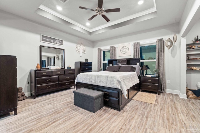 bedroom with ornamental molding, a tray ceiling, ceiling fan, and light hardwood / wood-style floors