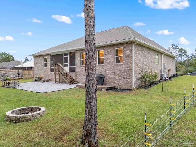 rear view of house with a yard, a fire pit, and a sunroom