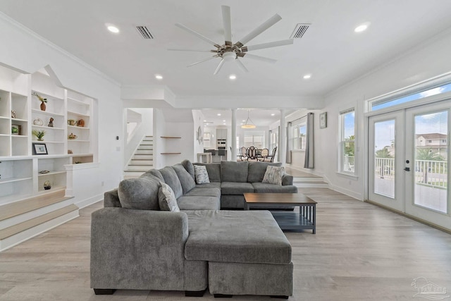 living room with crown molding, french doors, built in shelves, ceiling fan, and light hardwood / wood-style floors