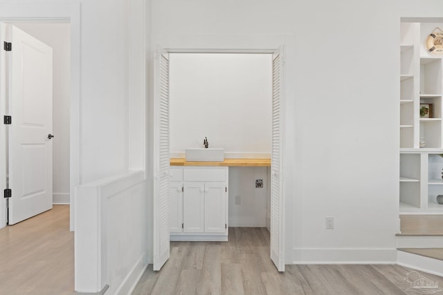 interior space featuring cabinets, sink, light hardwood / wood-style flooring, and electric dryer hookup