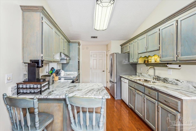 kitchen featuring sink, a breakfast bar area, white dishwasher, decorative light fixtures, and kitchen peninsula