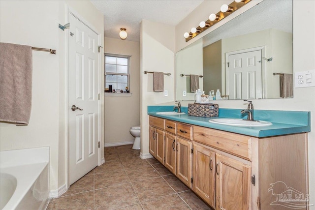 bathroom featuring tile patterned flooring, vanity, a bath, a textured ceiling, and toilet