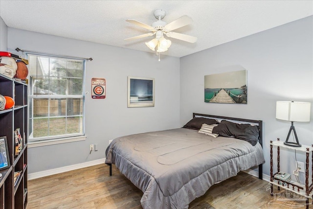 bedroom featuring ceiling fan, hardwood / wood-style floors, and a textured ceiling