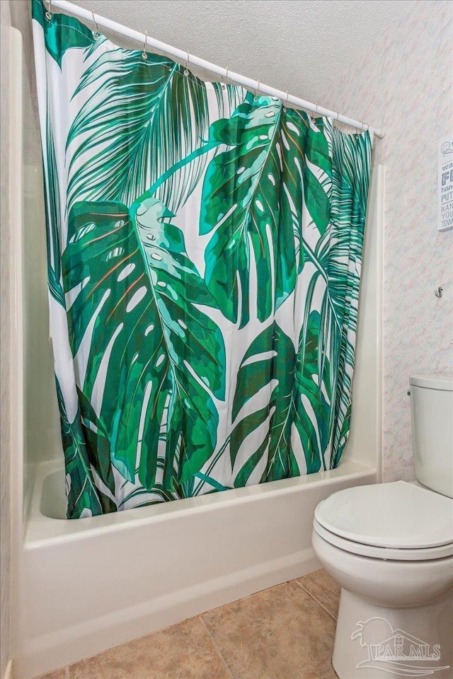 bathroom featuring tile patterned flooring, a textured ceiling, shower / bath combination with curtain, and toilet