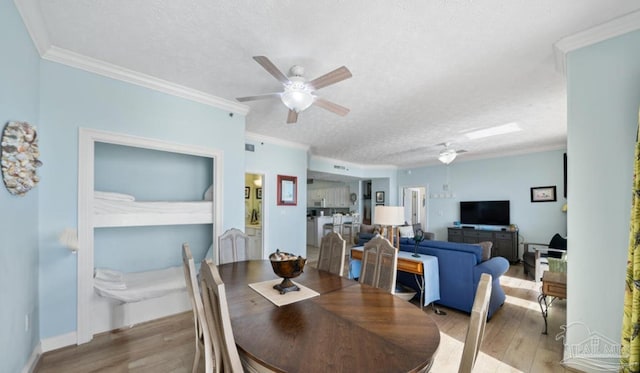 dining space featuring ornamental molding, light wood-type flooring, and a textured ceiling