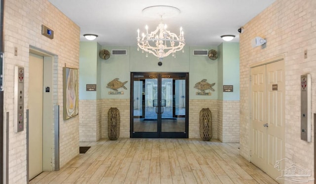 hallway featuring light wood finished floors, french doors, visible vents, and tile walls