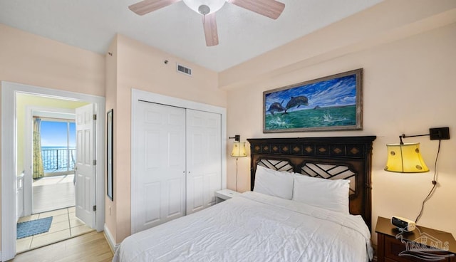 bedroom featuring light wood-style floors, ceiling fan, visible vents, and a closet