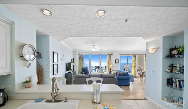 kitchen with open floor plan, light countertops, a textured ceiling, and a sink