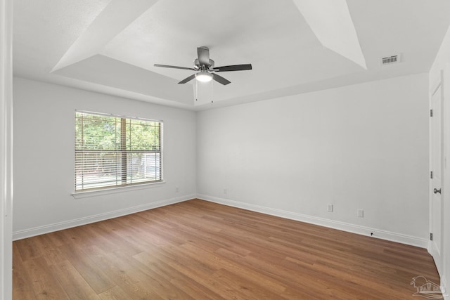 5473 Tucker Cir, Pace, FL 32571 - empty room featuring a tray ceiling, ceiling fan, wood finished floors, and baseboards