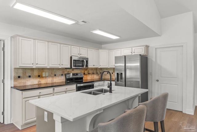 5473 Tucker Cir, Pace, FL 32571 - kitchen with appliances with stainless steel finishes, a sink, decorative backsplash, a breakfast bar, and light wood finished floors