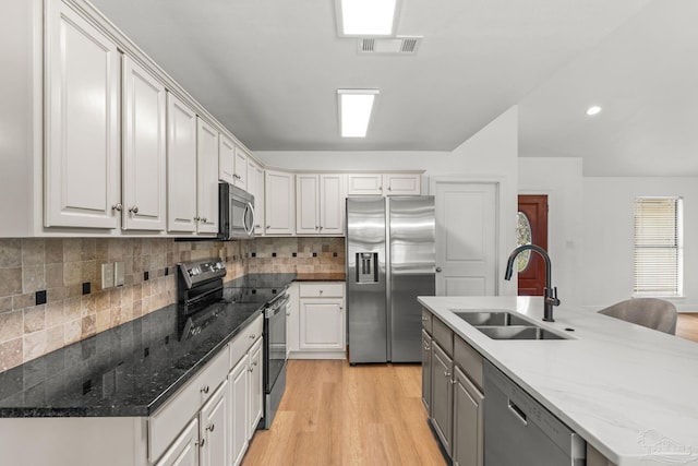 5473 Tucker Cir, Pace, FL 32571 - kitchen with appliances with stainless steel finishes, a sink, light wood-type flooring, white cabinetry, and tasteful backsplash