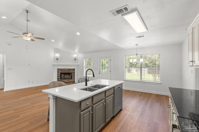 5473 Tucker Cir, Pace, FL 32571 - kitchen with dishwasher, a sink, a stone fireplace, baseboards, and light wood-style floors