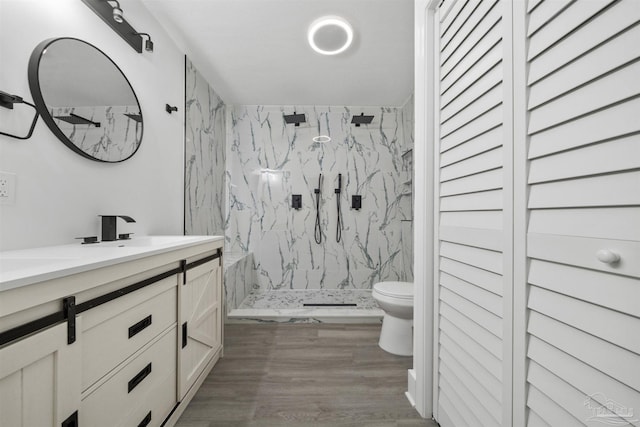 bathroom with vanity, toilet, wood-type flooring, and a tile shower