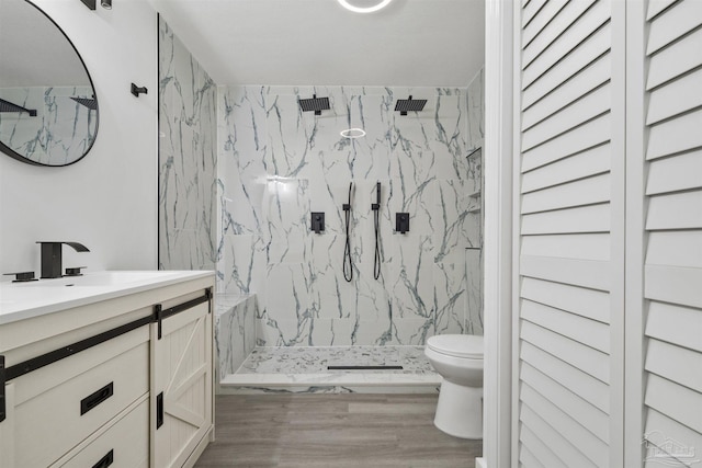 bathroom featuring hardwood / wood-style floors, vanity, a tile shower, and toilet