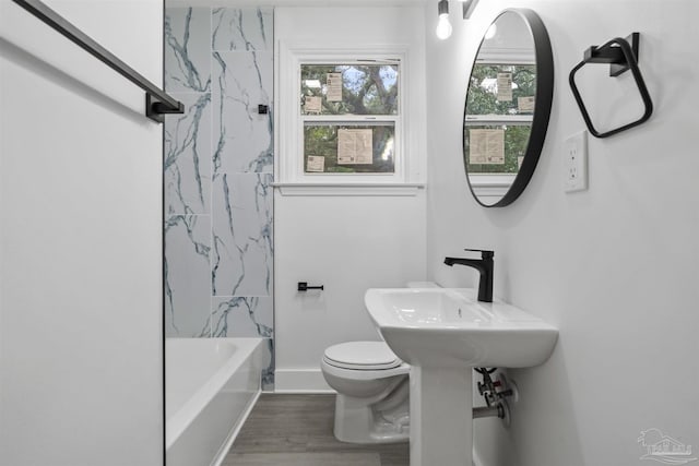 bathroom with hardwood / wood-style floors, tiled shower / bath combo, and toilet