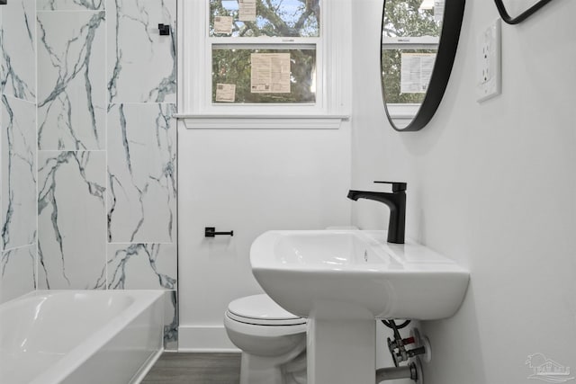 bathroom with hardwood / wood-style floors, tiled shower / bath combo, toilet, and plenty of natural light