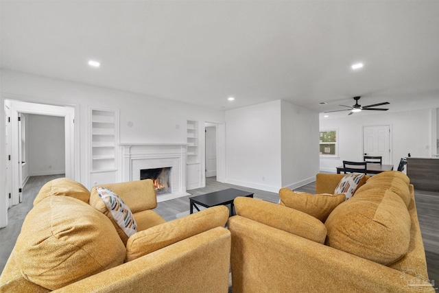 living room with hardwood / wood-style flooring, built in shelves, and ceiling fan