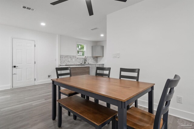 dining area with ceiling fan, light wood-type flooring, and sink