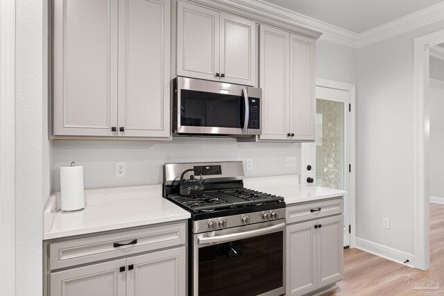 3041 Mountain Laurel Trl, Cantonment, FL 32533 - kitchen with light wood-style floors, appliances with stainless steel finishes, ornamental molding, and light countertops