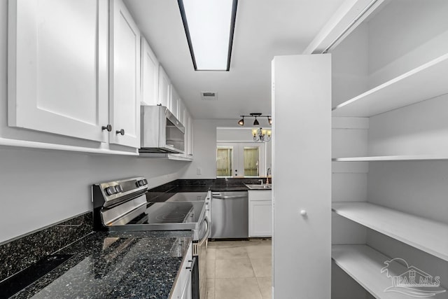 kitchen featuring white cabinets, appliances with stainless steel finishes, dark stone countertops, sink, and light tile patterned floors