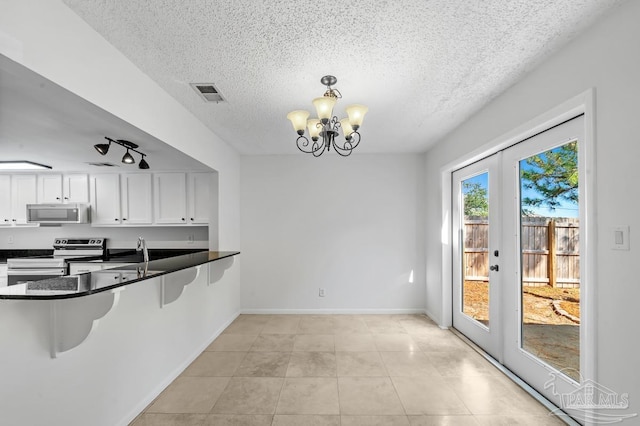 kitchen featuring kitchen peninsula, white cabinets, stainless steel appliances, and french doors