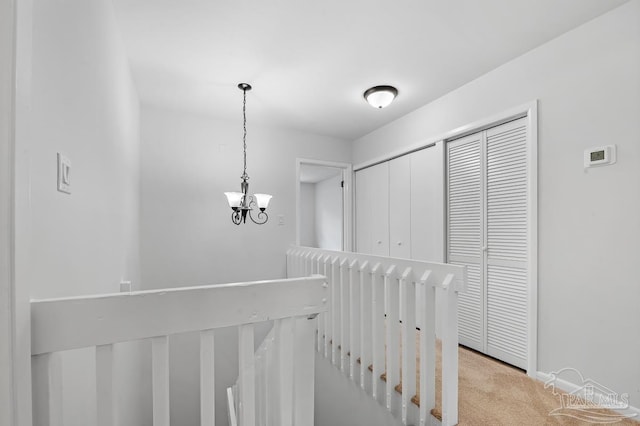 hall with light carpet and a chandelier