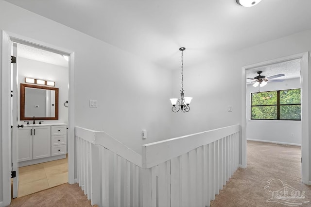 hallway with sink, a notable chandelier, and light carpet