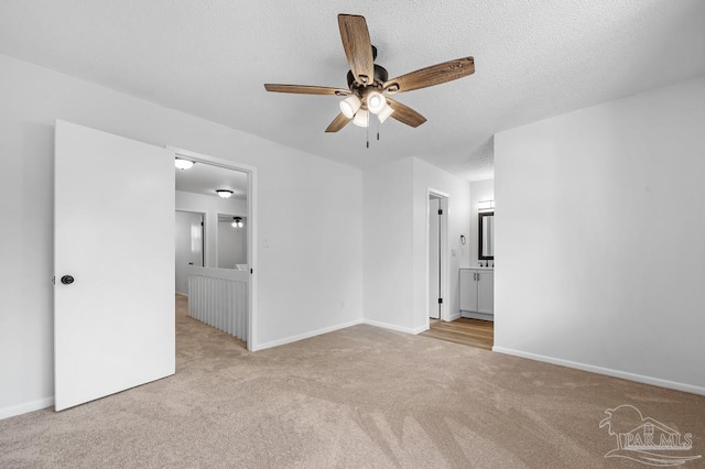 empty room featuring a textured ceiling, light colored carpet, and ceiling fan