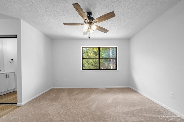 carpeted empty room featuring ceiling fan and a textured ceiling