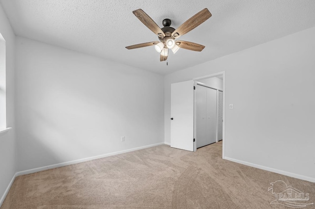 carpeted empty room featuring ceiling fan and a textured ceiling