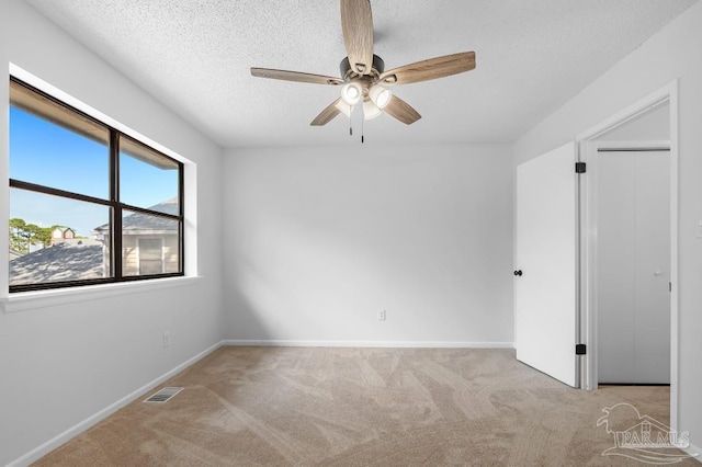 unfurnished room with ceiling fan, light colored carpet, and a textured ceiling