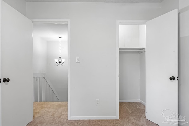 unfurnished bedroom featuring a closet, an inviting chandelier, and light carpet