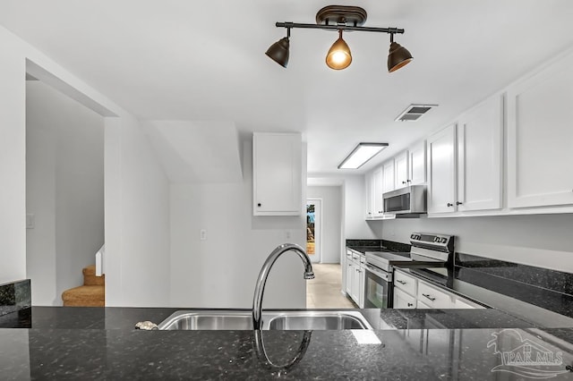 kitchen featuring dark stone countertops, stainless steel appliances, white cabinetry, and sink