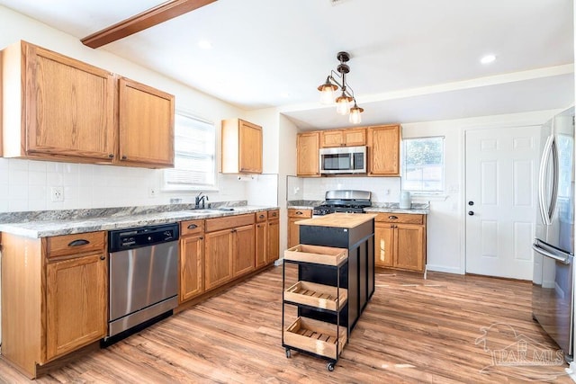 kitchen featuring appliances with stainless steel finishes, a center island, light hardwood / wood-style flooring, and a healthy amount of sunlight