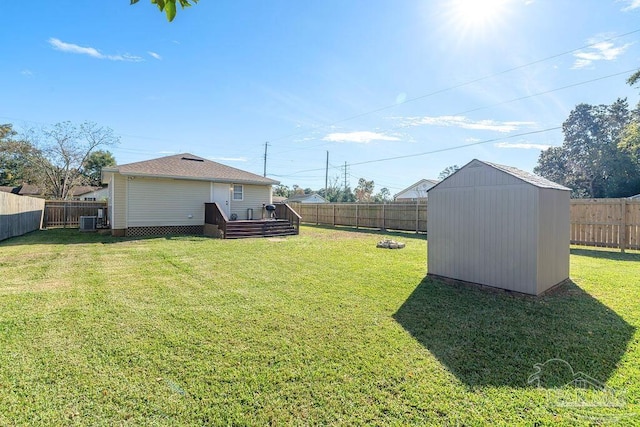 view of yard with central AC, a wooden deck, and a storage shed