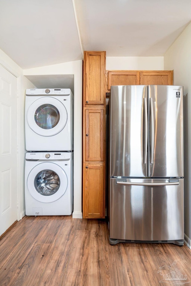 laundry area featuring dark hardwood / wood-style flooring and stacked washer / drying machine