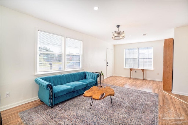 living room with an inviting chandelier, a healthy amount of sunlight, and hardwood / wood-style flooring