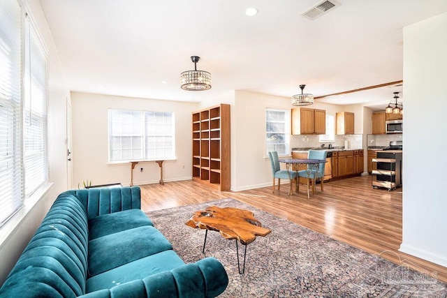 living room with sink, an inviting chandelier, and light wood-type flooring