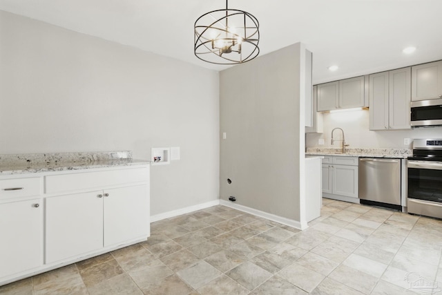 4741 Huron Dr, Pensacola, FL 32507 - kitchen with recessed lighting, light stone counters, an inviting chandelier, baseboards, and appliances with stainless steel finishes