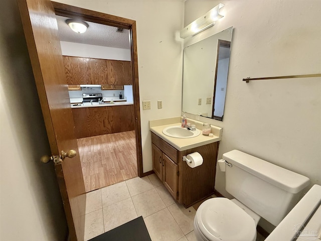 bathroom featuring tile patterned flooring, vanity, a textured ceiling, and toilet