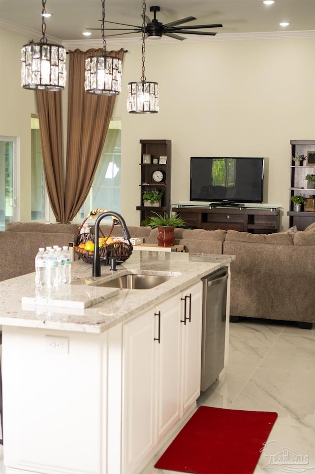 kitchen featuring sink, a kitchen island with sink, hanging light fixtures, white cabinetry, and light stone countertops