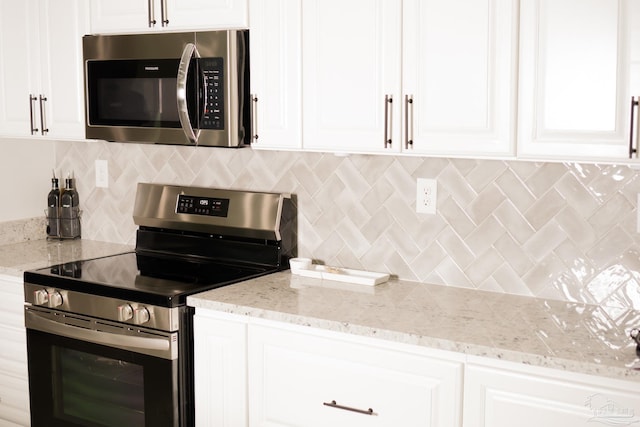 kitchen featuring white cabinetry, backsplash, light stone countertops, and appliances with stainless steel finishes