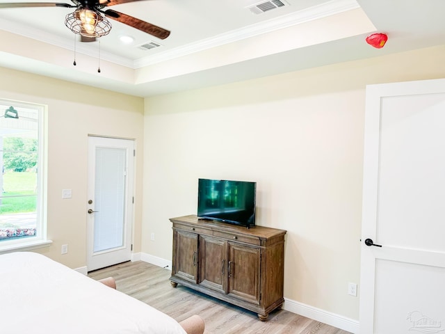 bedroom featuring crown molding, light wood-type flooring, and a tray ceiling